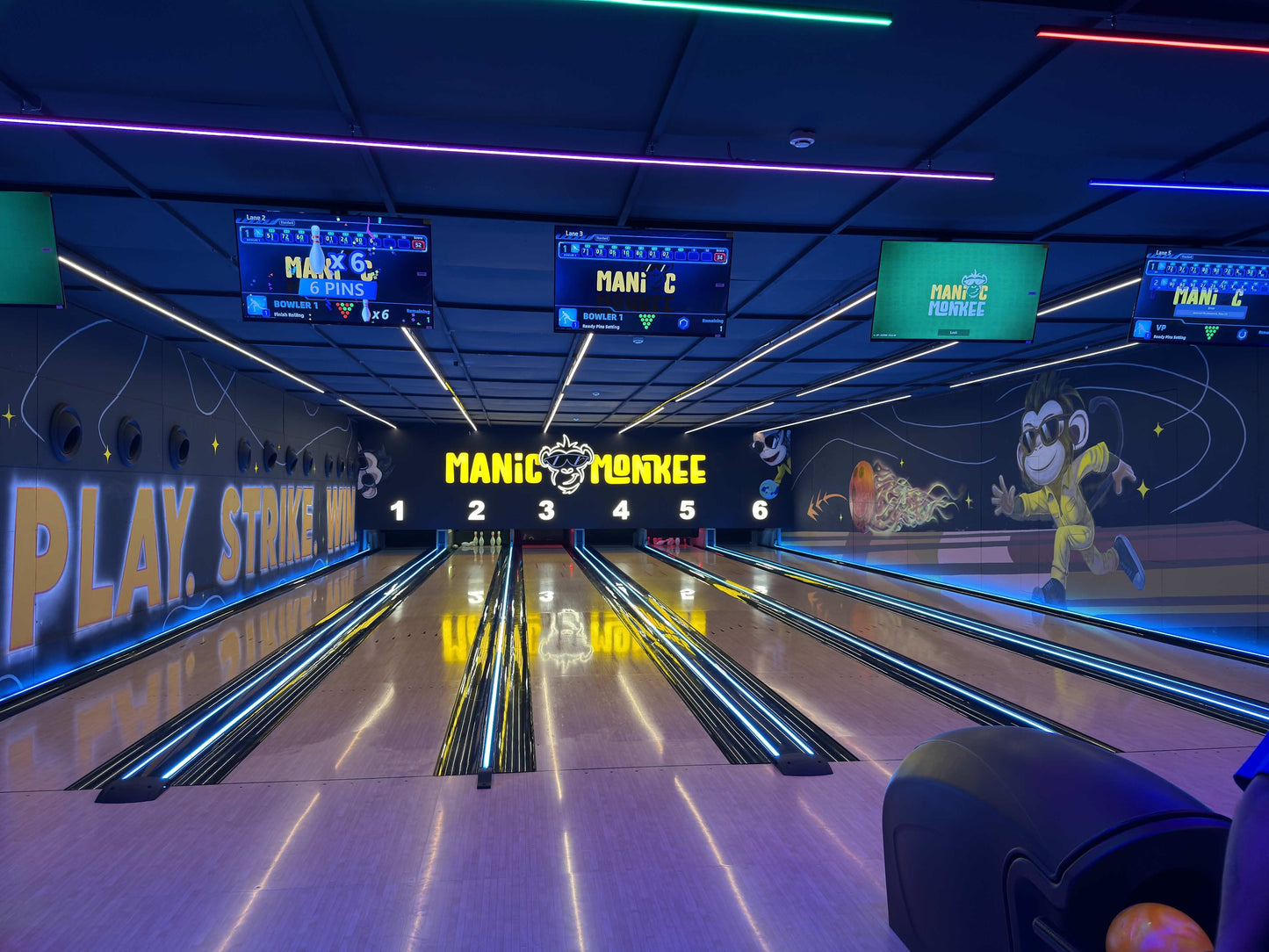 A bowling alley with neon lights and a "Manic Monkey" theme, showing multiple lanes and scoreboards.