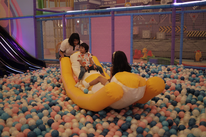 Children play in a ball pit with a woman supervising.