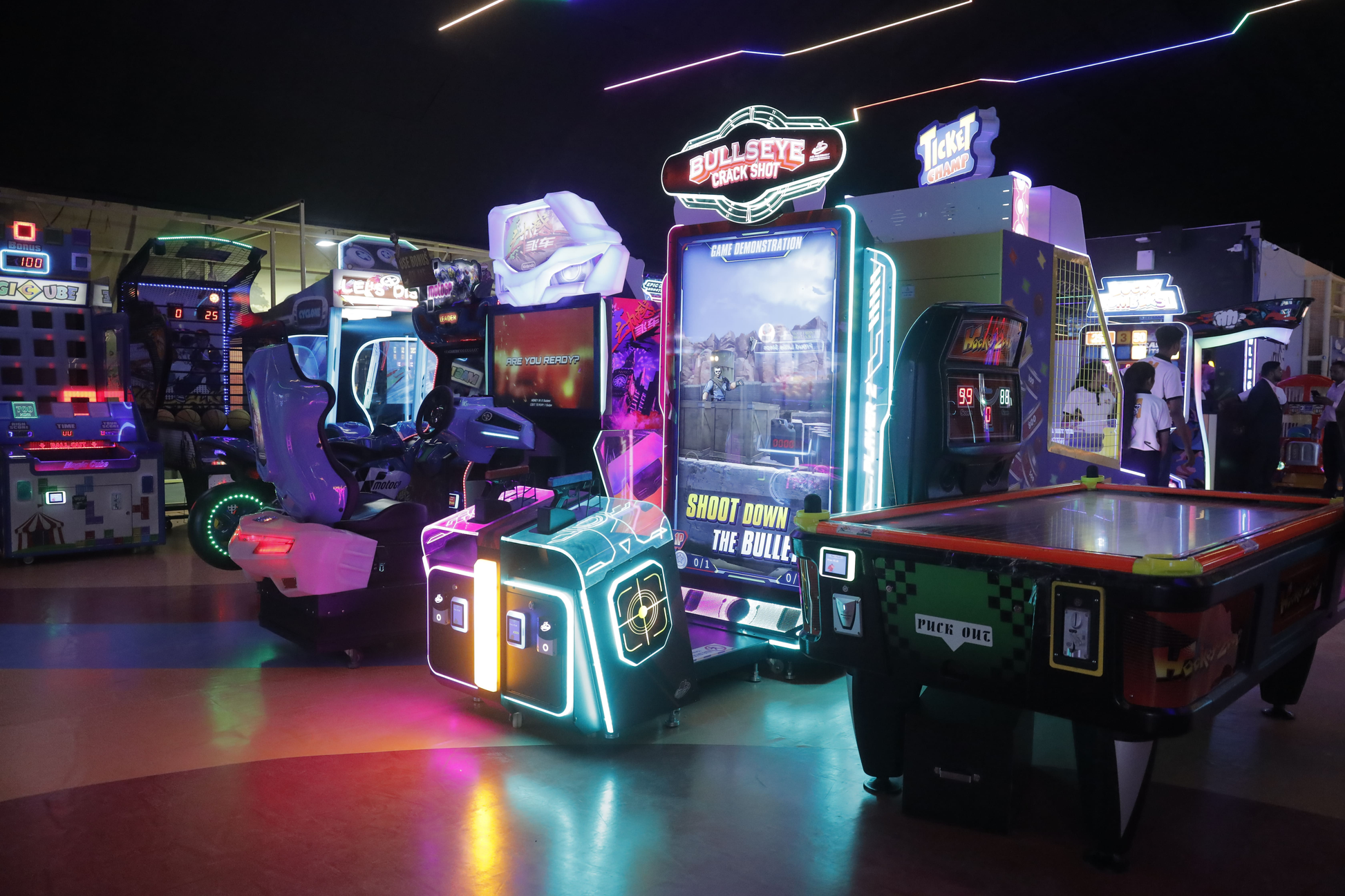 An arcade with various game machines and a few young people playing.