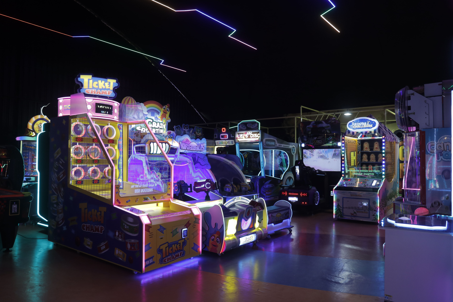 An arcade with colorful, lit-up game machines and neon lights.