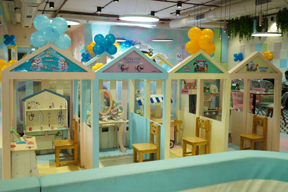Playhouses for children, including a doctor's office, salon, and shop, are decorated with balloons.
