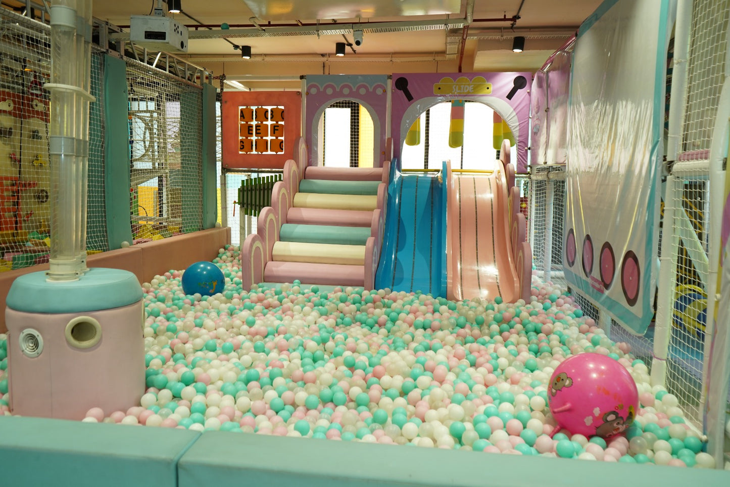 A ball pit filled with colorful balls, featuring slides and climbing structures for young children.