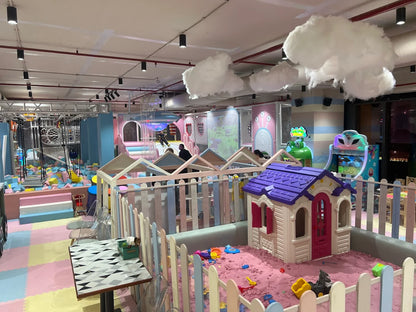 A colorful indoor playground with a ball pit, sandpit, and playhouse for children.
