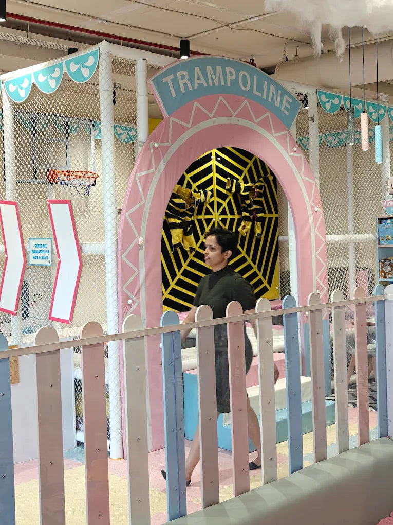 A woman walks past a colorful indoor trampoline park with a "Trampoline" sign.