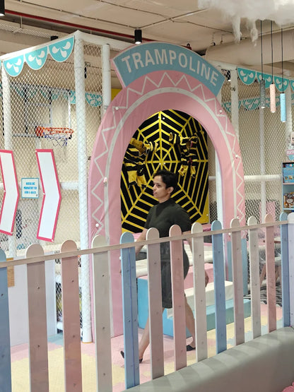 A woman walks past a colorful indoor trampoline park with a "Trampoline" sign.