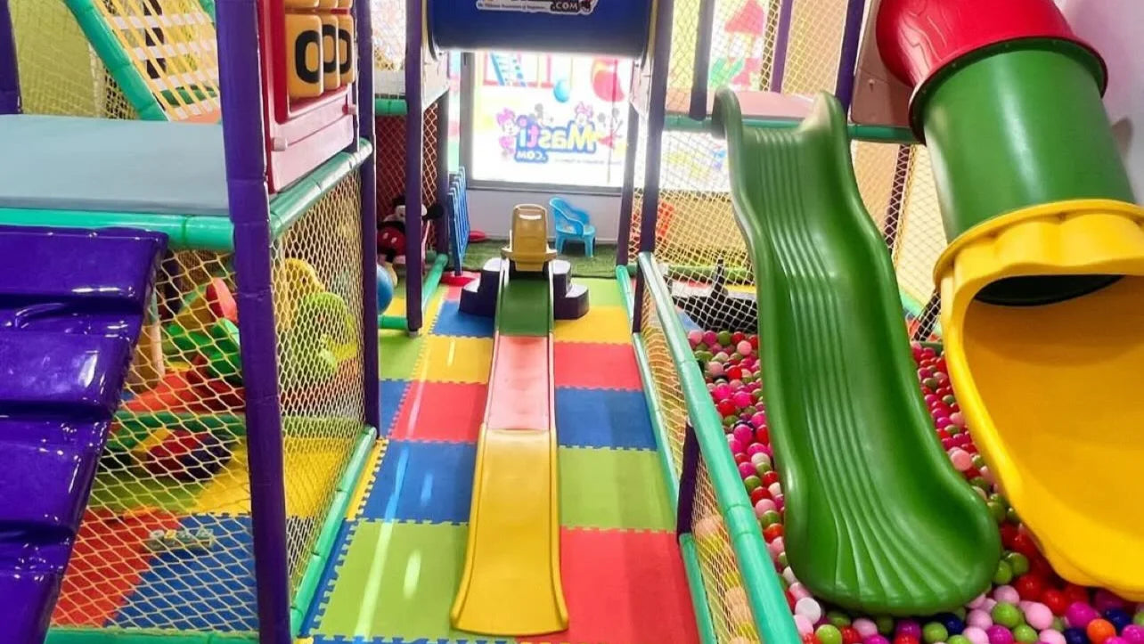 A colorful indoor playground with slides and a ball pit, designed for young children.