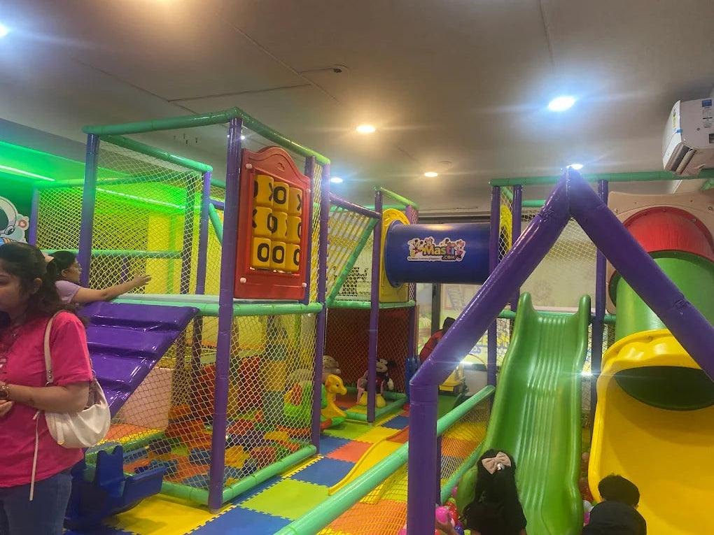 A colorful indoor playground with slides and climbing structures, where children are playing.