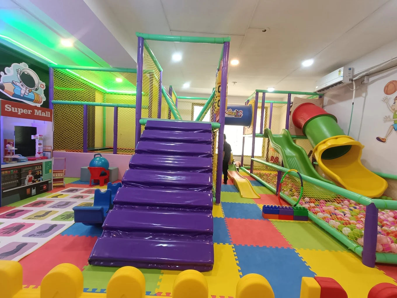 A colorful indoor playground with slides, ball pit, and climbing structures for children.