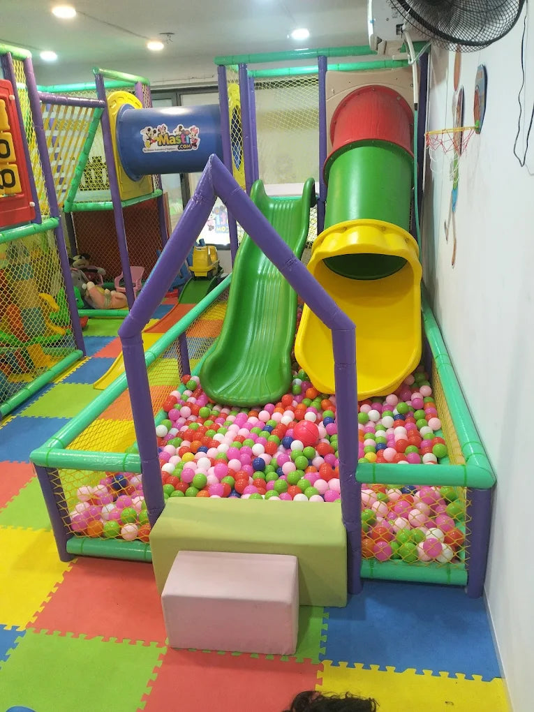 A colorful indoor playground with slides, a ball pit, and climbing structures for young children.