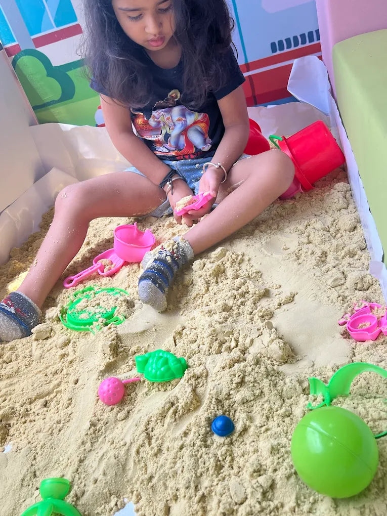 A young child plays with sand toys in a sandbox.
