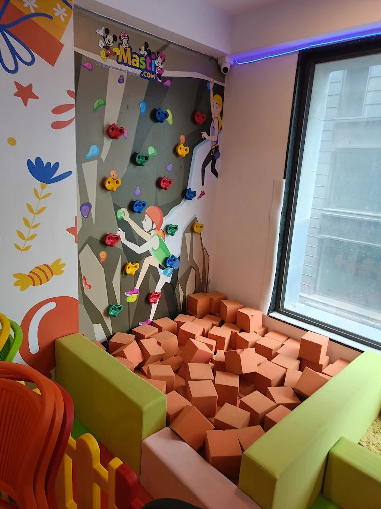 A climbing wall with colorful holds and a foam pit for children.