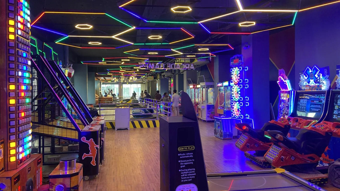 An arcade with colorful neon lights, game machines, and people playing.