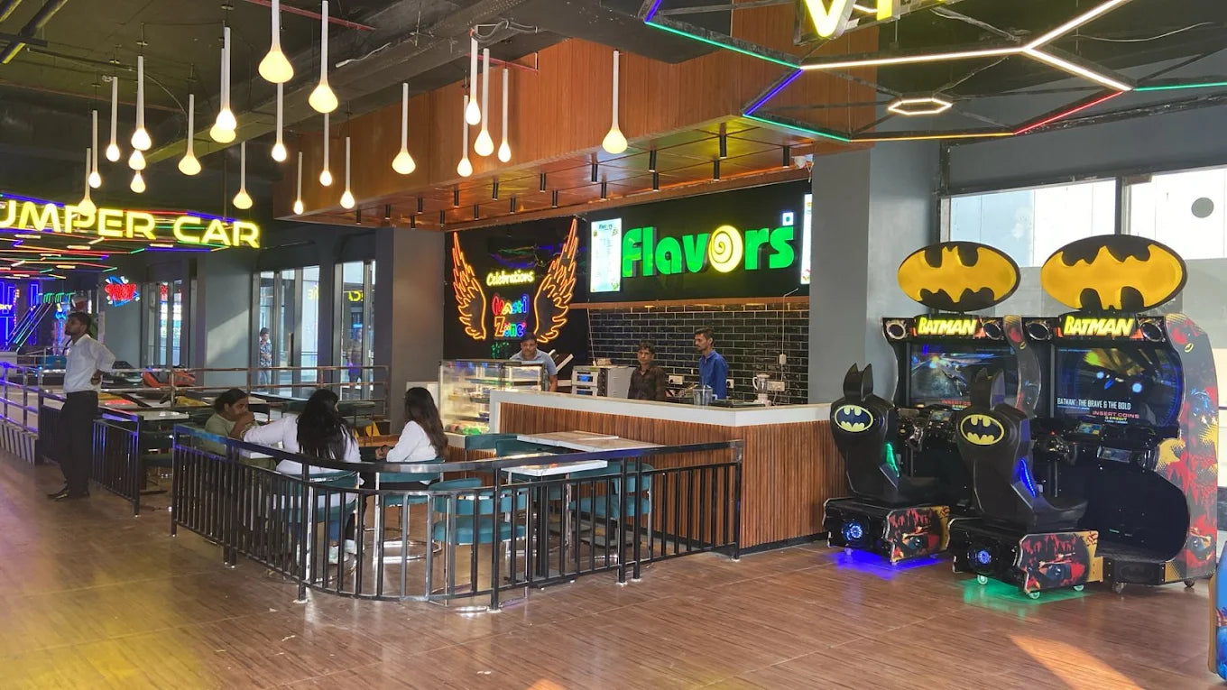 People at an arcade with Batman games and a food counter.