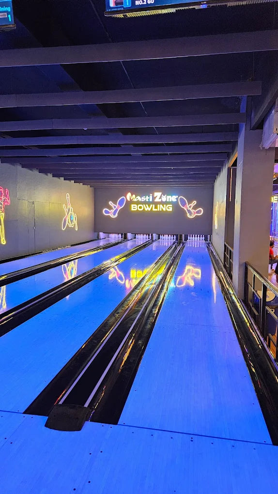 A bowling alley with glowing blue lanes and neon signs.