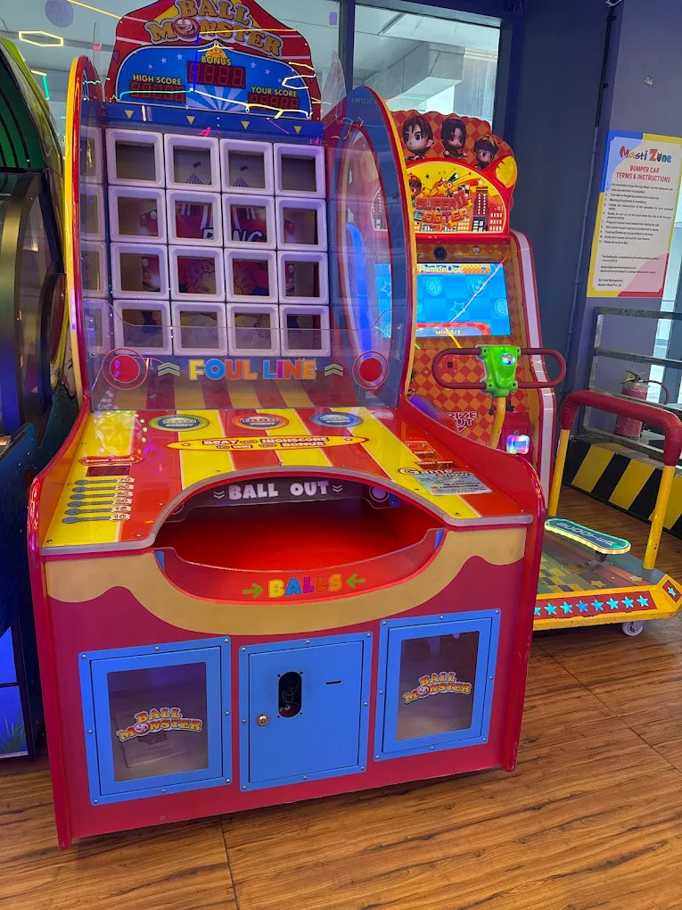 Colorful arcade game machine with various buttons and displays on a wooden floor.