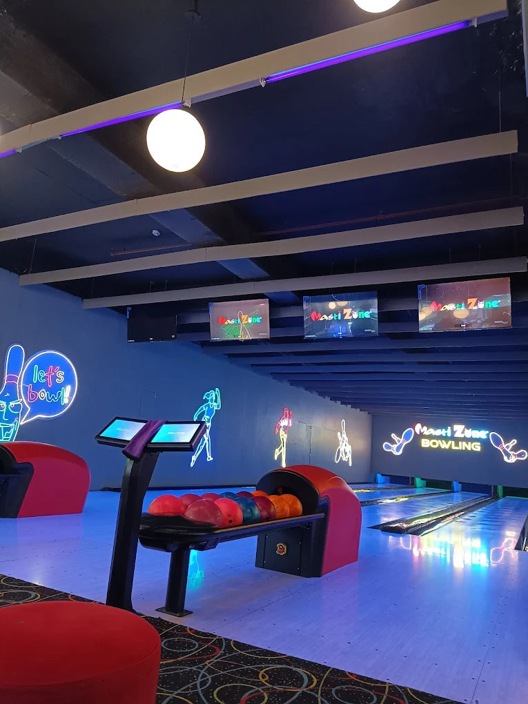 A bowling alley with neon lights and bowling balls on a rack.