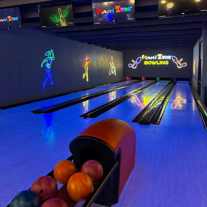 Bowling alley with lanes and a ball return area, featuring colorful bowling balls and illuminated signs.