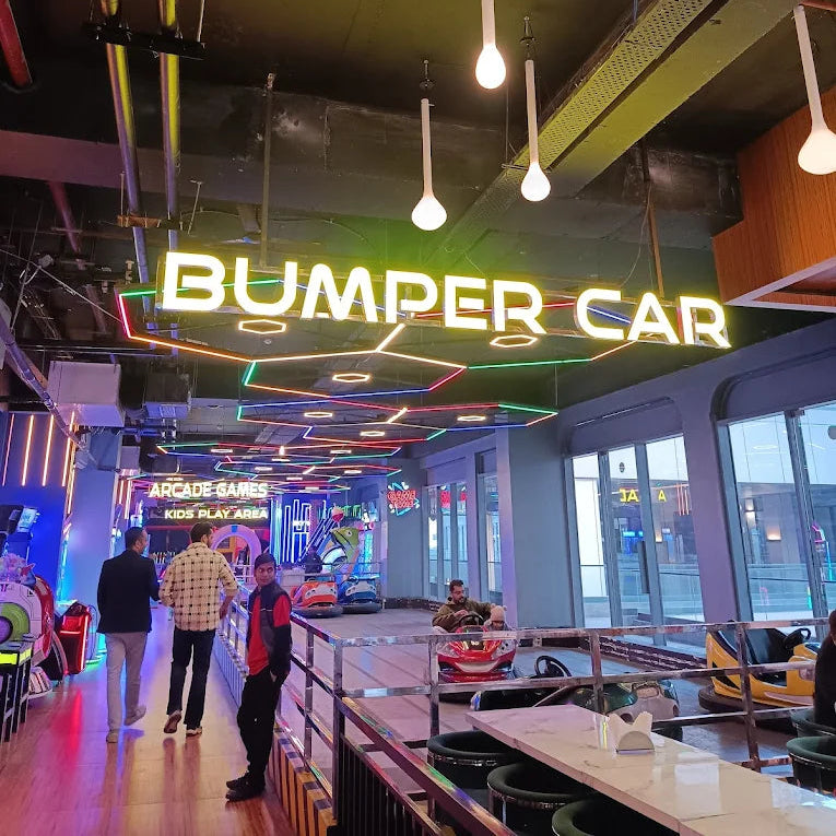 Indoor amusement park with 'Bumper Car' sign and people walking around.