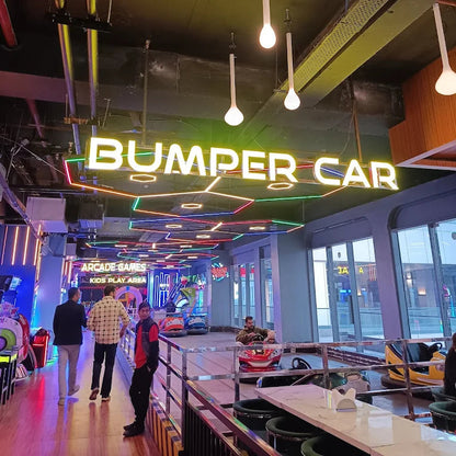Indoor amusement park with 'Bumper Car' sign and people walking around.