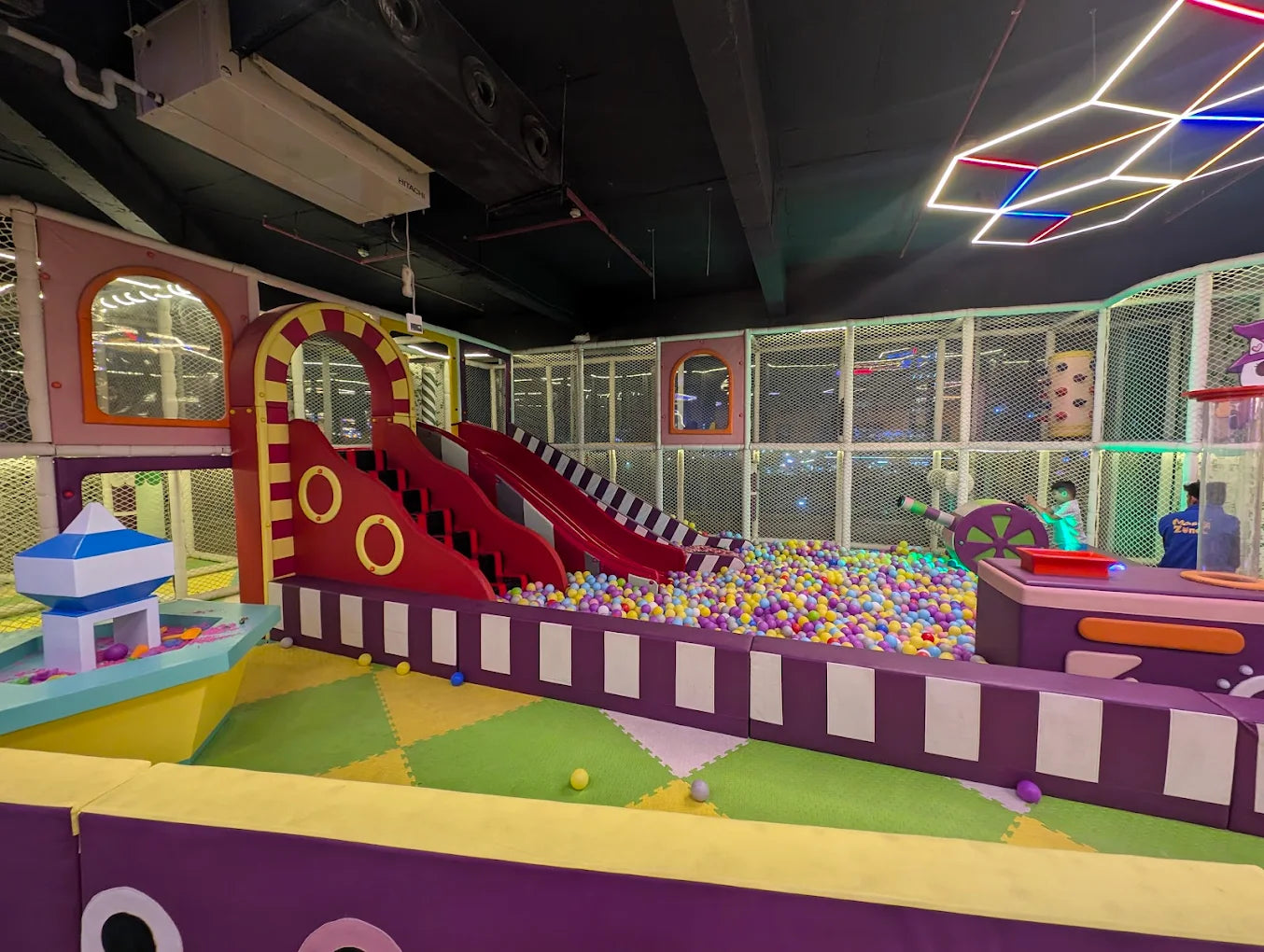 A colorful indoor playground with ball pits, slides, and young children playing.
