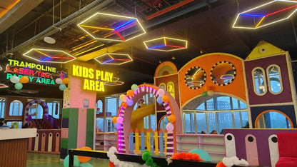 A vibrant indoor kids' play area with colorful structures, trampolines, and neon lights.