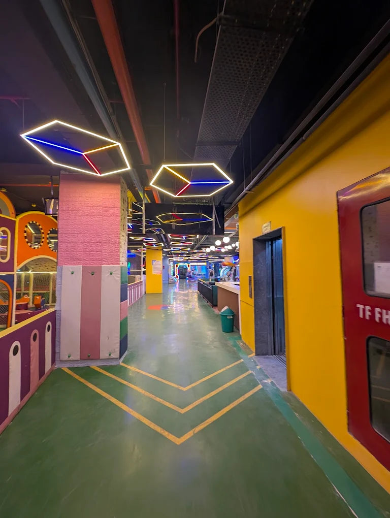 A brightly colored indoor play area with geometric lights and a green floor.