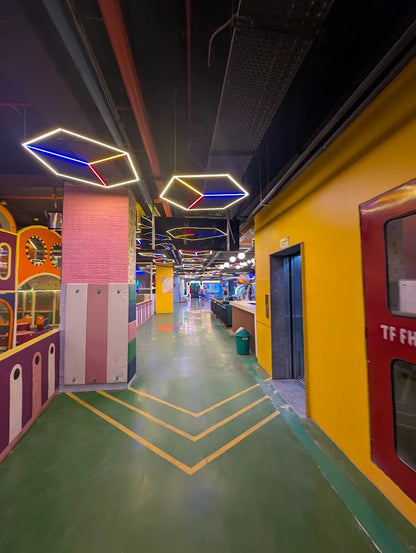 A brightly colored indoor play area with geometric lights and a green floor.