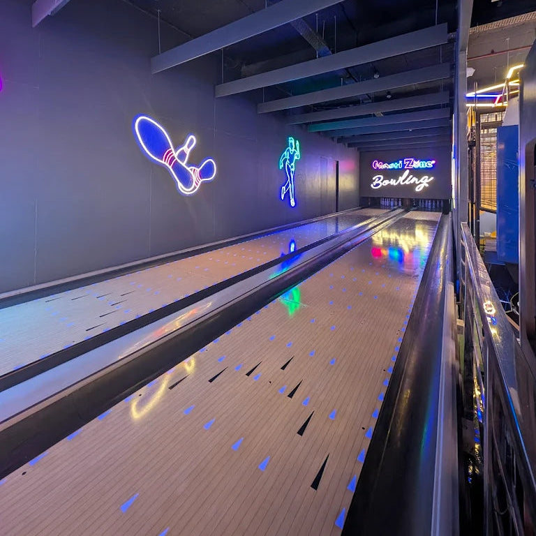 Neon bowling alley sign on a wall with a lane in the foreground