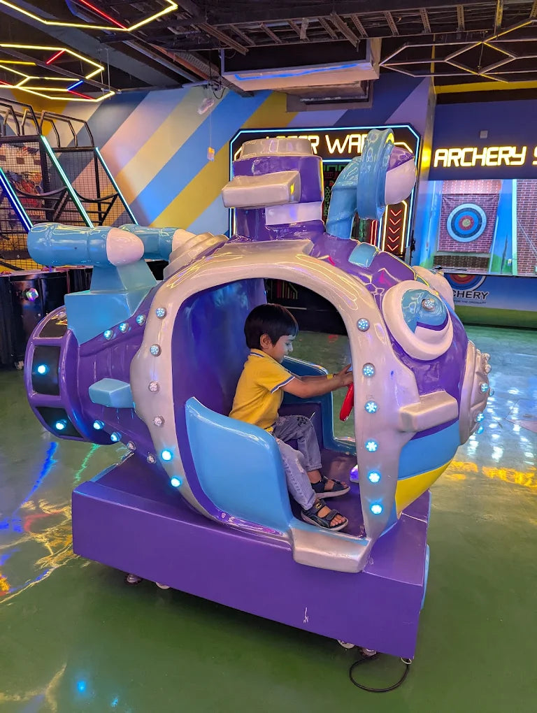 Child playing on a colorful arcade game in an indoor amusement area.