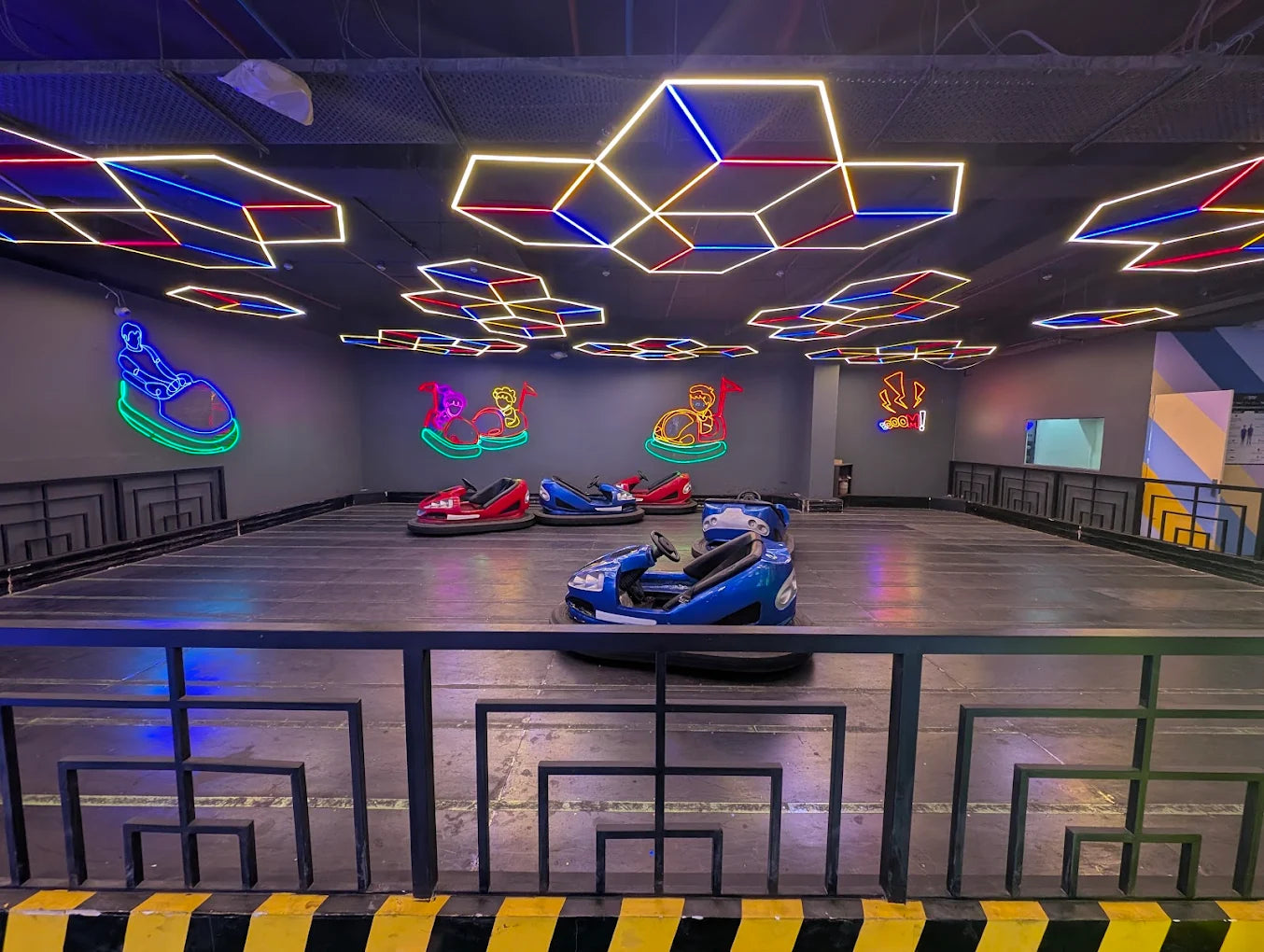 Indoor amusement park with bumper cars and colorful ceiling lights.