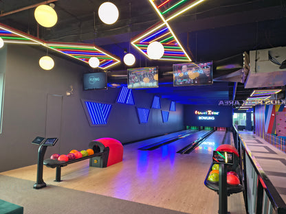 A bowling alley with neon lights and screens showing sports.