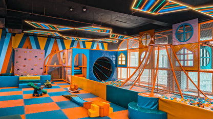 A colorful indoor playground with slides, ball pits, and climbing walls for children.