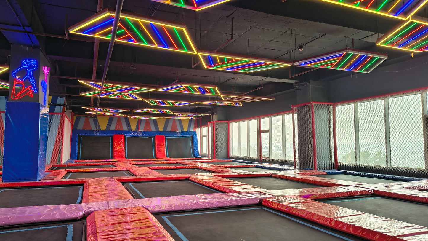 An indoor trampoline park with colorful neon lights and multiple trampolines.