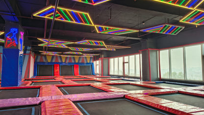 An indoor trampoline park with colorful neon lights and multiple trampolines.
