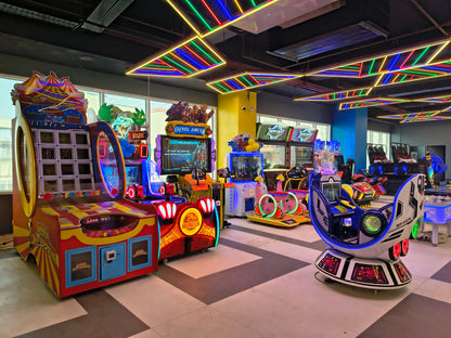 Colorful arcade machines in an indoor gaming area with a checkered ceiling.