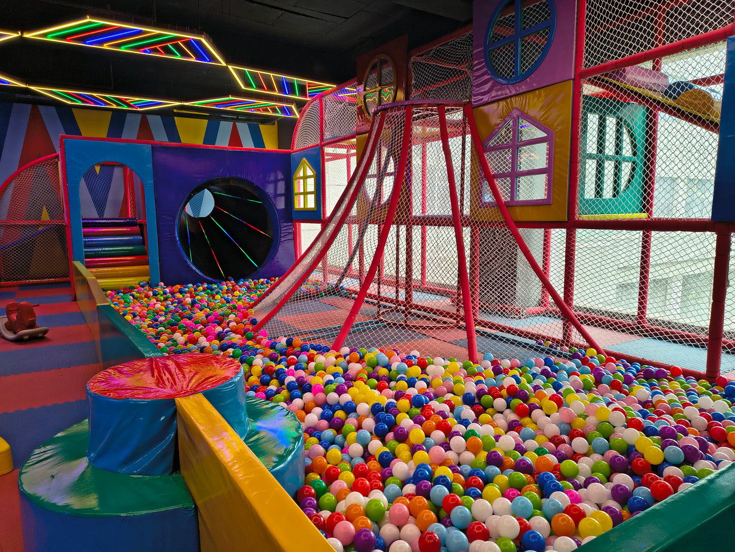 A colorful indoor playground with a ball pit and slides, designed for young children.
