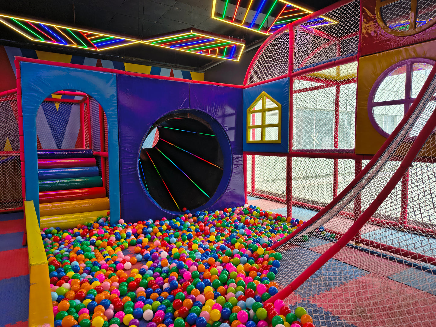 A colorful indoor playground with a ball pit and neon lights.
