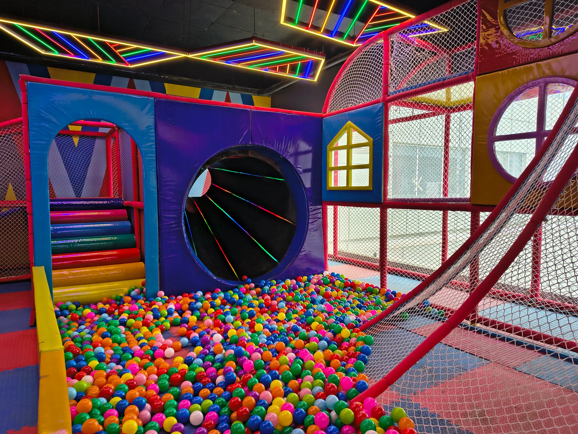 A colorful indoor playground with a ball pit and neon lights.
