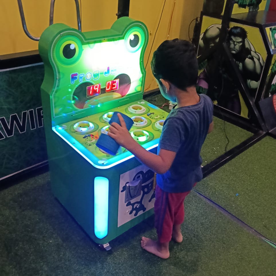 Child playing a frog-themed arcade game in an indoor setting