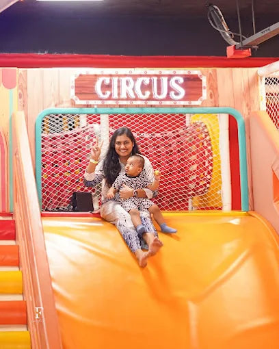 A woman and a toddler slide down an orange play structure.