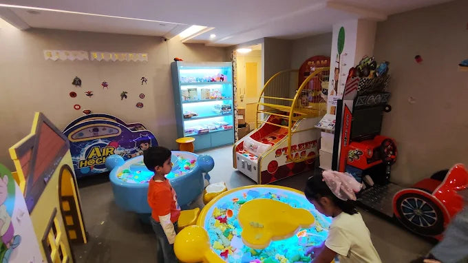 Children play in an arcade with colorful games and a ball pit.