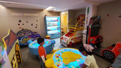 Children play in an arcade with colorful games and a ball pit.