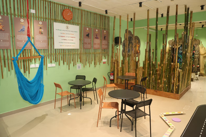 A bright blue hammock hangs in a room decorated with bamboo, with tables and chairs for children.