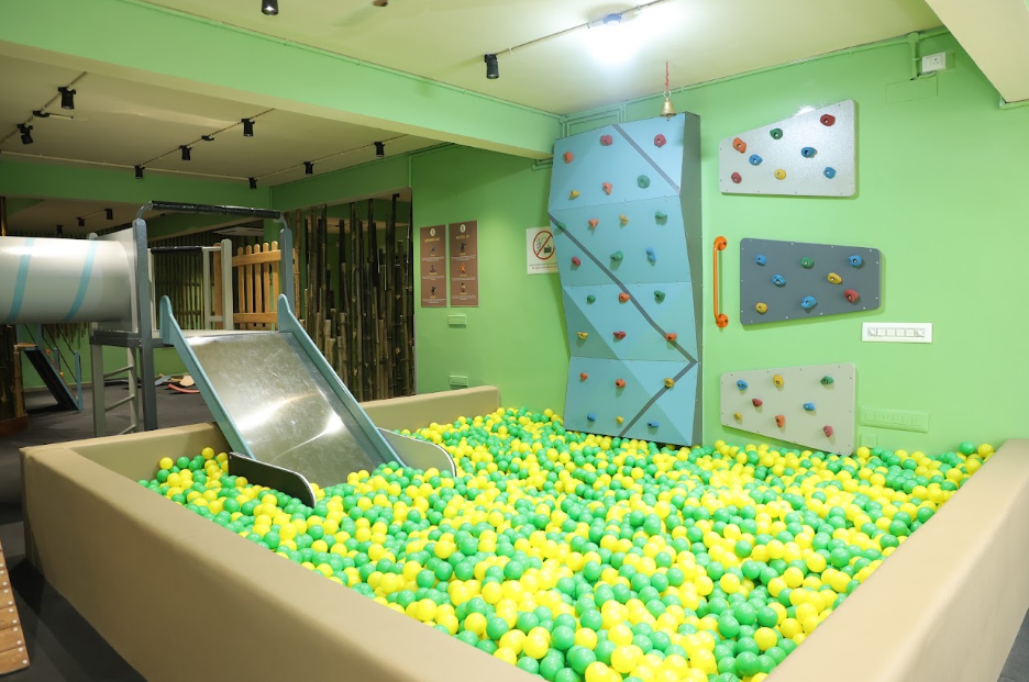 A children's indoor playground with a ball pit, slide, and climbing wall.
