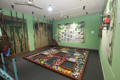 A room with a large Lego play area for children, surrounded by bamboo decor and a jungle-themed mural.