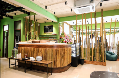 A cafe with bamboo decor, a counter displaying pastries, and a green beanbag chair.
