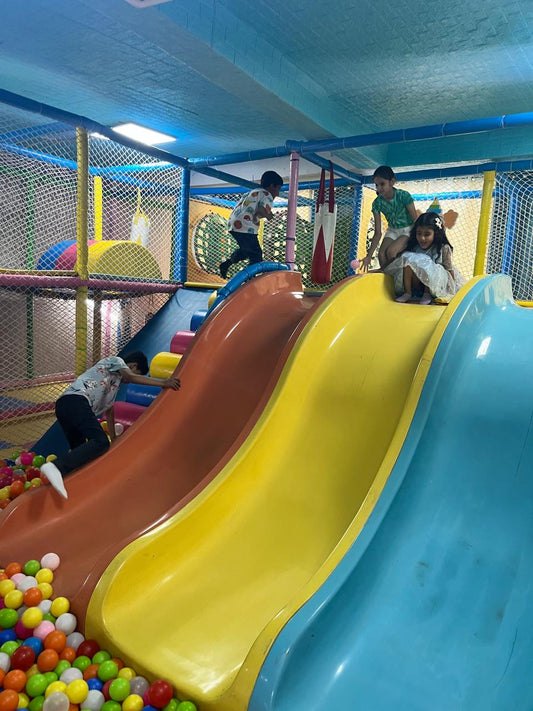 Children playing on a colorful indoor playground with slides and ball pit.