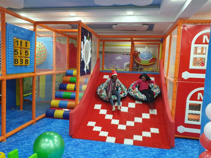 Children playing in a colorful indoor playground with slides and play structures.
