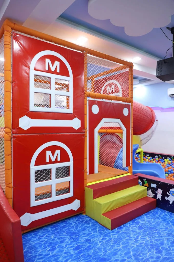 Children's play area with a red playhouse and slide in an indoor playground.