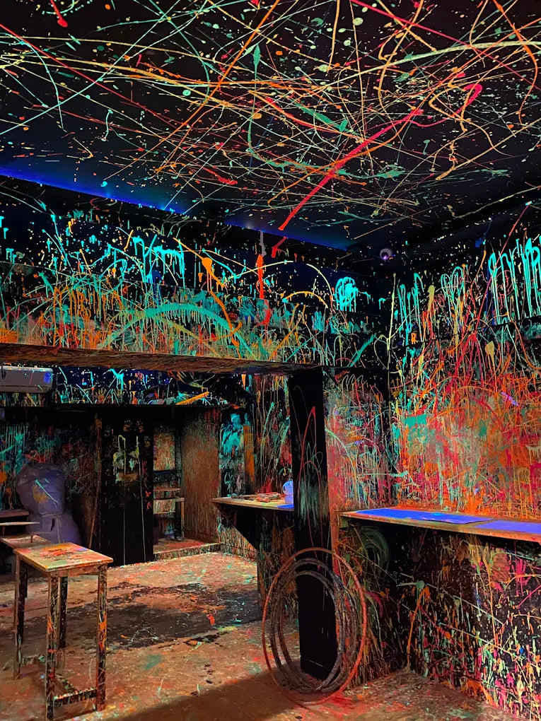 A room covered in neon paint splatters, with tables and counters also painted.